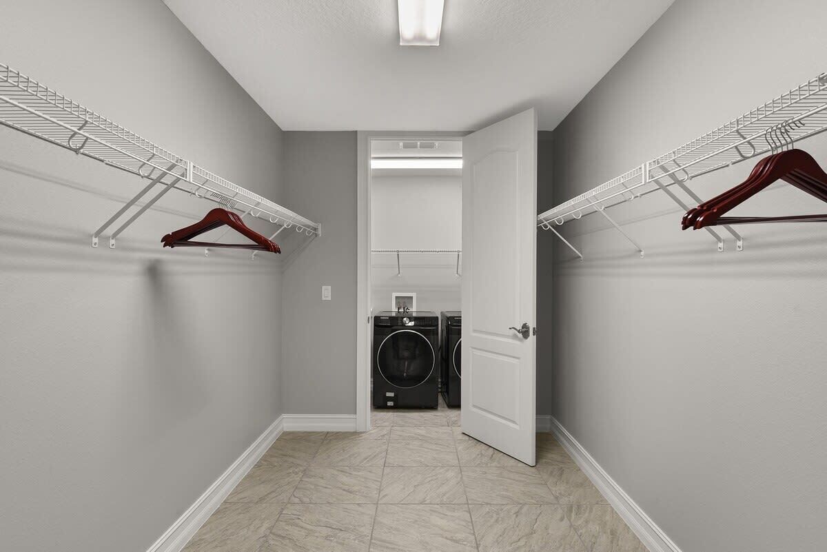 Une buanderie avec une porte donnant sur une salle de bain, un lave-linge et un sèche-linge.