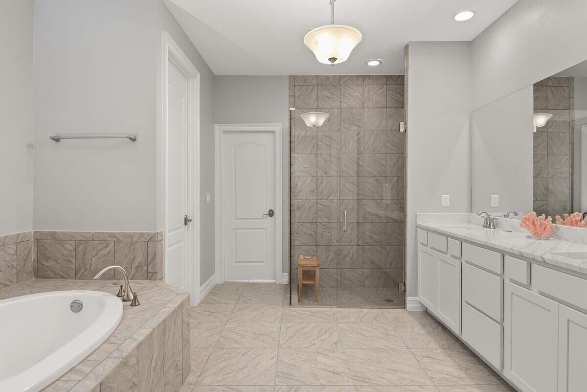 Une salle de bain moderne avec une baignoire, une douche à portes en verre et un meuble-lavabo doté d’un grand miroir.