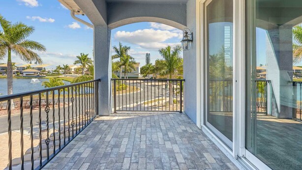 A balcony with a view of a body of water, palm trees, and buildings in the background. - Fortebello Beachside 170 With PRIVATE POOL (Indian Harbour Beach)