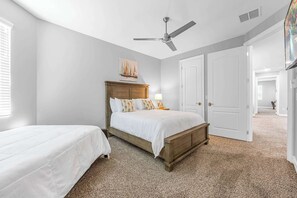 Un dormitorio con cama, mesita de noche, ventilador de techo y una puerta.