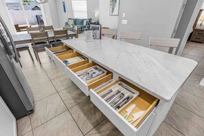 Une cuisine moderne dotée d’un plan de travail en marbre, de nombreux tiroirs et d’un coin repas avec des chaises et une table.