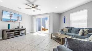 A living room with a TV, sofa, coffee table, and a ceiling fan. - Fortebello Beachside 170 With PRIVATE POOL (Indian Harbour Beach)