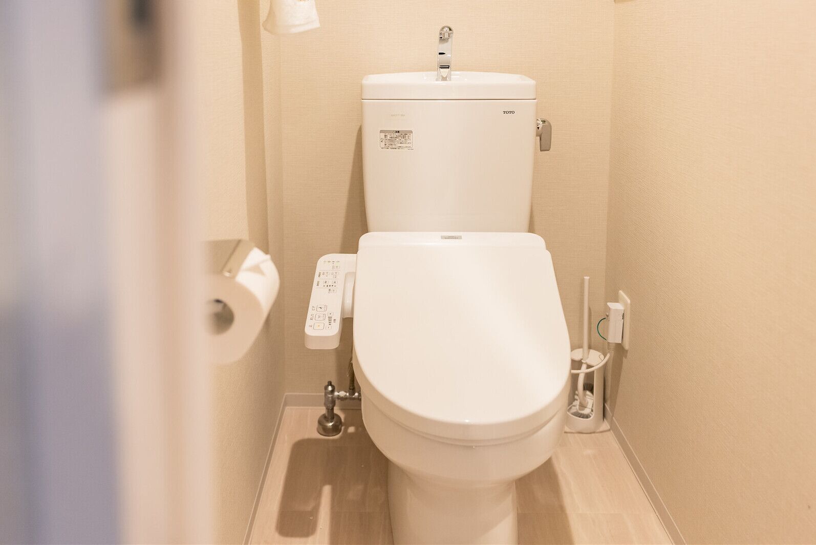 A toilet with a control panel and a toilet paper holder.