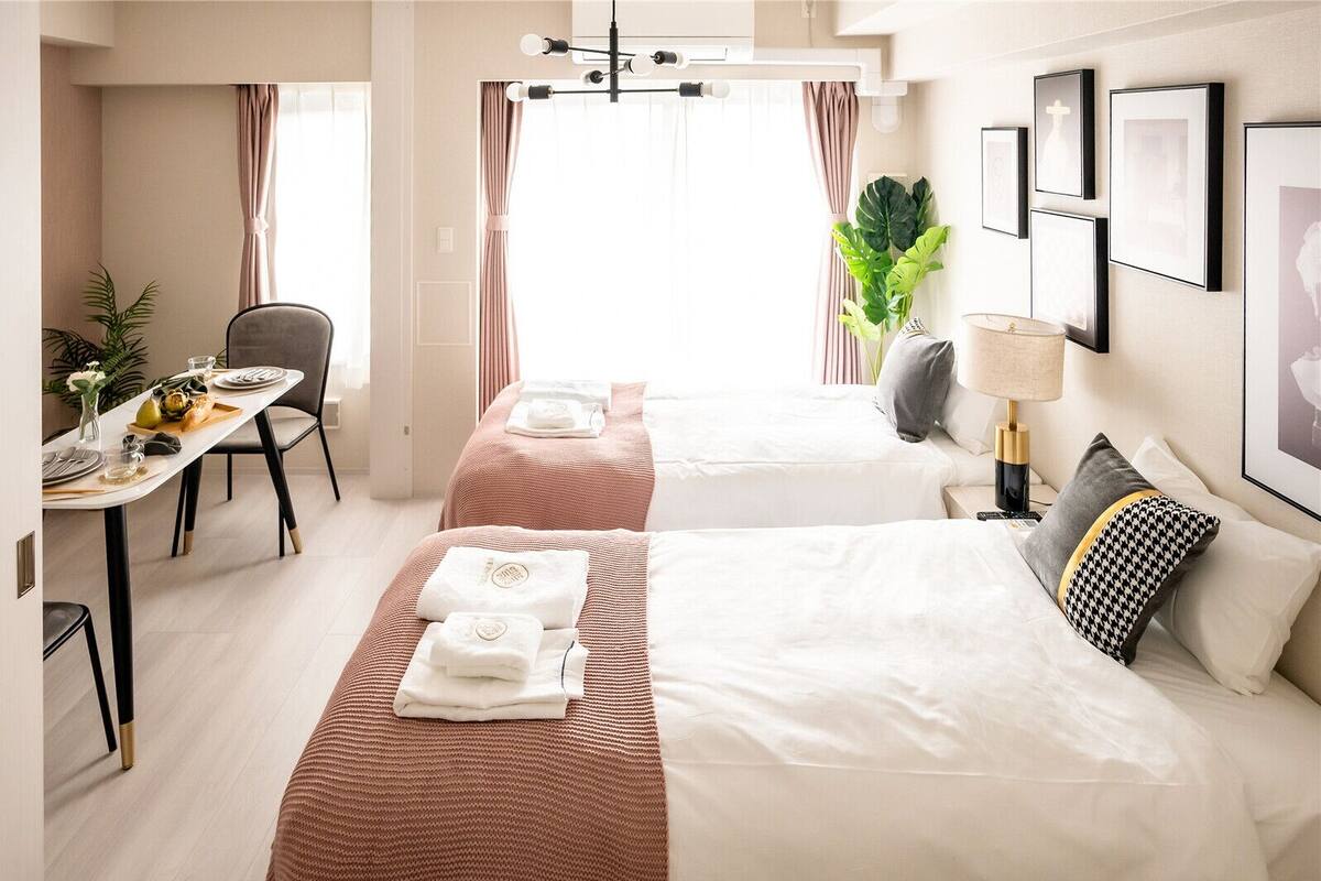A hotel room with two beds, a dining area, and a view of the city.