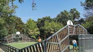 Un terrain de basket-ball entouré d’une clôture en bois et équipé d’un panier de basket.
