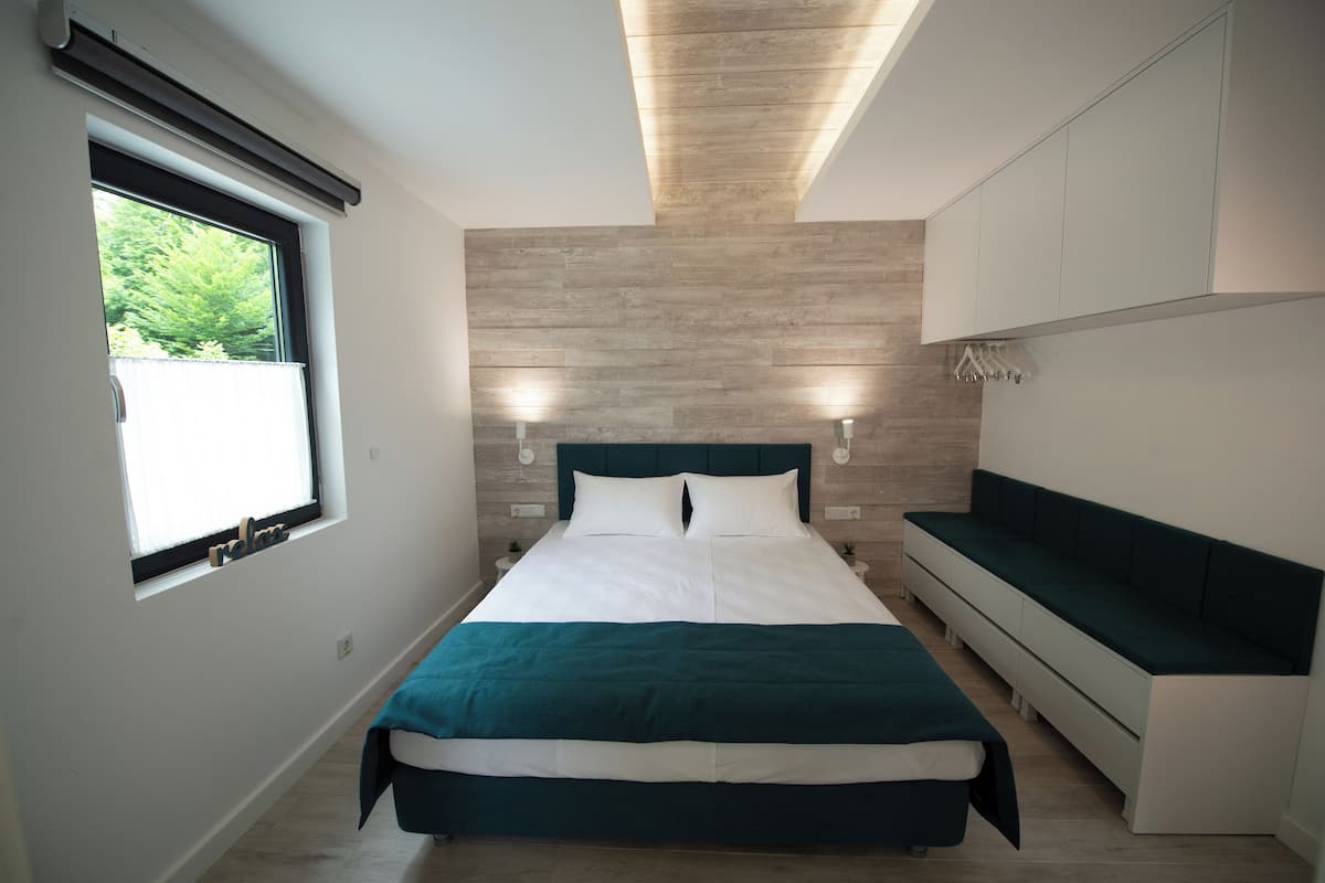 A modern bedroom with a bed, a bench, and a window.