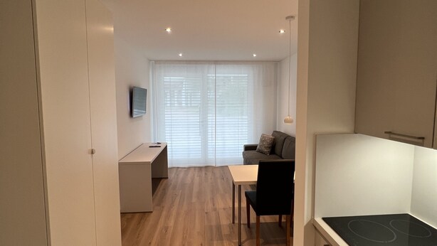 Una cocina moderna con estufa integrada, piso de madera y un comedor con mesa y sillas.