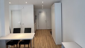 Una habitación moderna y minimalista con suelo de madera, paredes blancas y una zona de comedor con mesa y sillas.