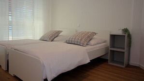 Un dormitorio con una cama, dos almohadas, una mesita de noche y una pequeña planta.