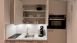 Cocina compacta con horno integrado, cafetera y lavamanos.