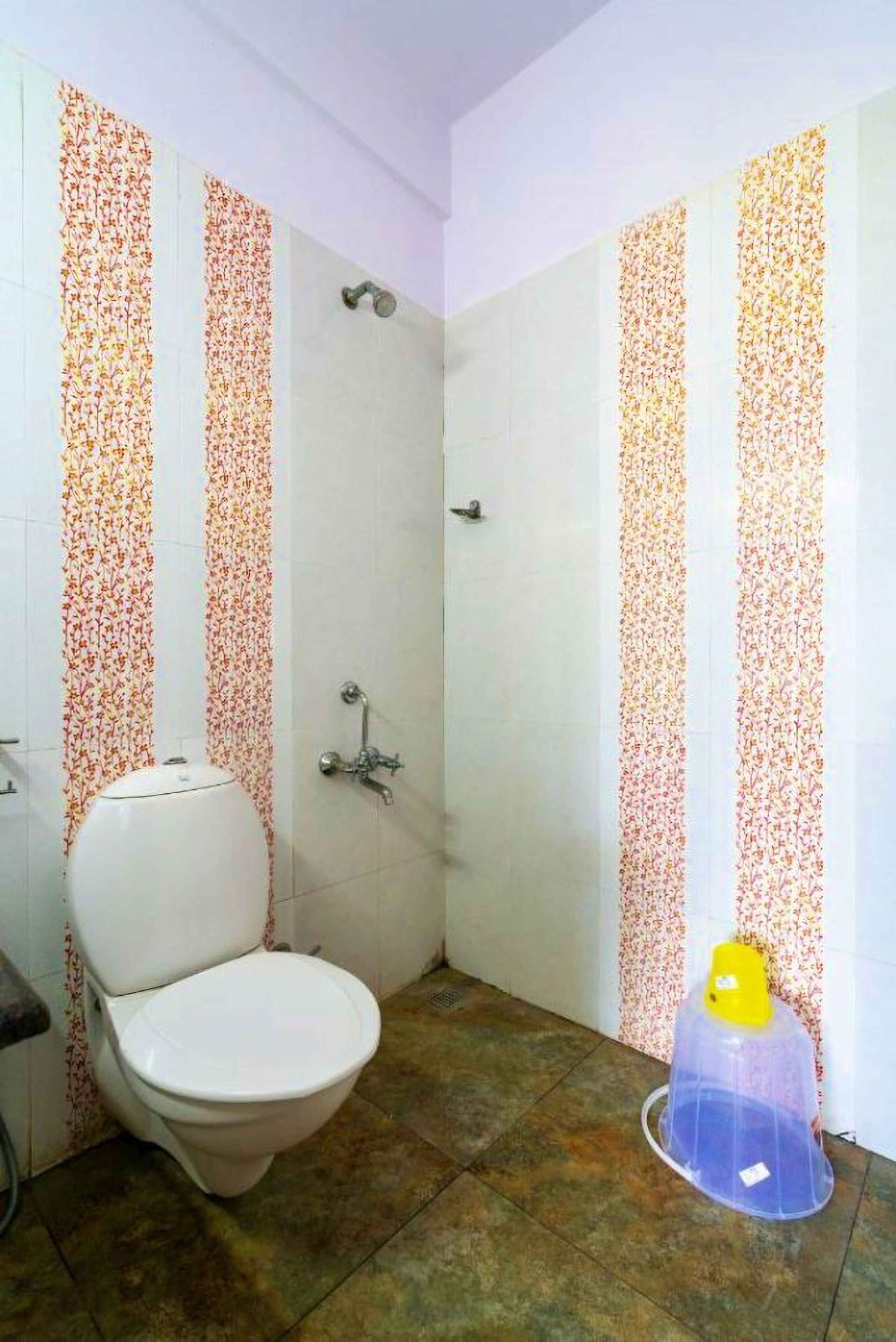 A small bathroom with a toilet, shower, and a plastic container on the floor.