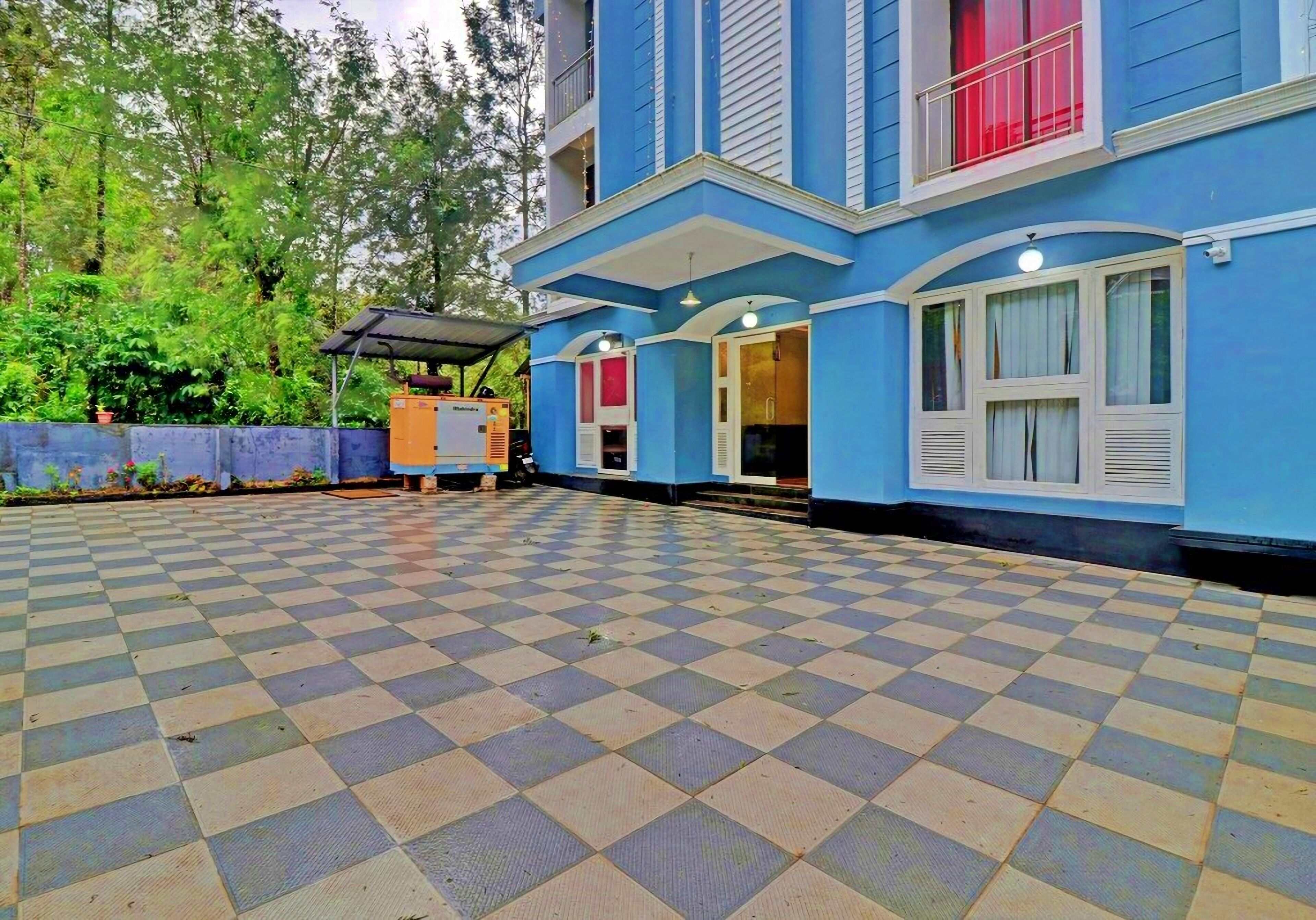 Un edificio blu con pavimento a scacchi, un balcone e una zona coperta con tavolo e sedie.