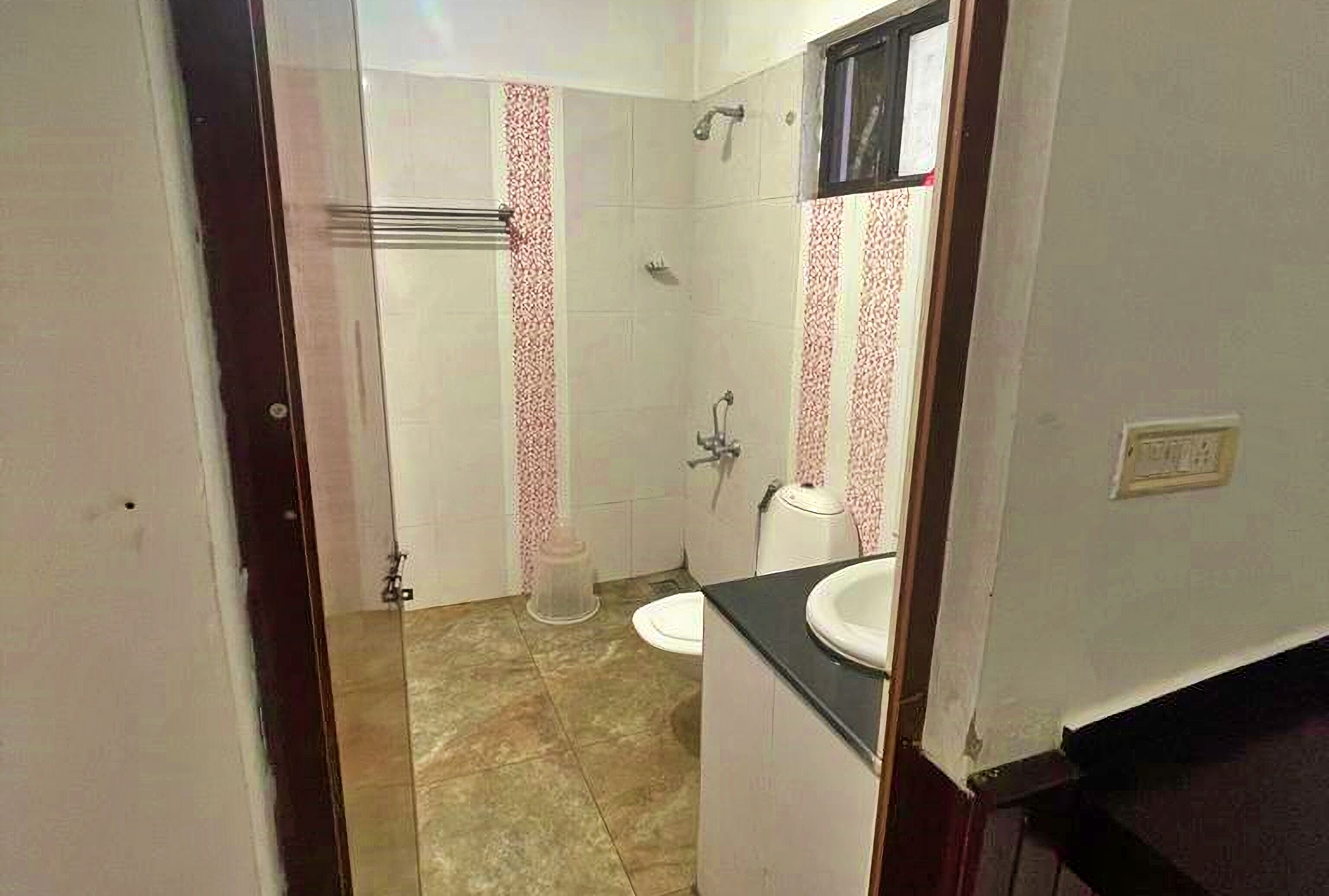 A bathroom with a toilet, sink, shower, and a towel rack.