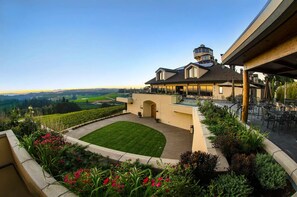 Un bâtiment moderne doté d’un grand patio, d’un espace extérieur couvert aménagé en coin salon et offrant une vue sur le paysage environnant.