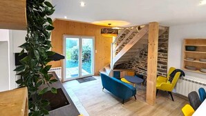 A modern living room with a staircase, wooden walls, and a large window.