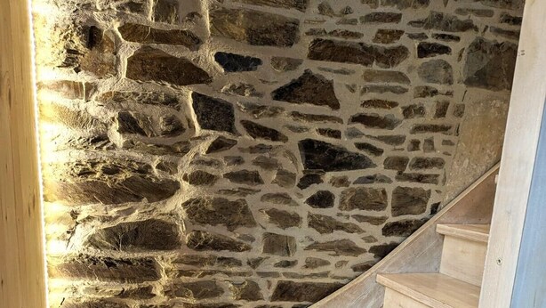 A spiral staircase with wooden steps and a stone wall.