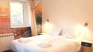 A bedroom with a bed, bedside tables, a window, and a wall mural.