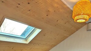 A room with a sloped ceiling, a skylight, a blue sofa, and a hanging light fixture.