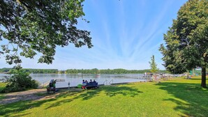 Un parc au bord du lac, avec une pelouse, un quai et quelques personnes.