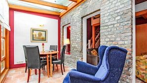 Une pièce comprenant une table à manger, des chaises, un fauteuil bleu, une lampe et un tableau accroché au mur.