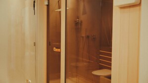 Et badeværelse med en brusekabine med glasvægge, toilet og vask.