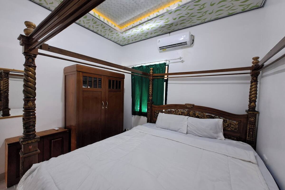 Un dormitorio con una cama con dosel, un armario de madera y un ventilador de techo.