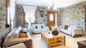 A cozy room with stone walls, two sofas, a wooden coffee table, and a chandelier.