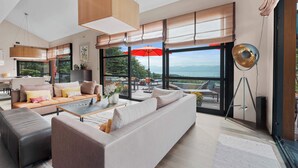 Una sala de estar moderna con sofá, reposapiés, mesa de centro y un gran ventanal con vistas.