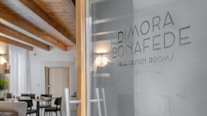 A modern interior with a glass door displaying the name "DIMORA BONAFEDE" and "IBLA DESIGN ROOMS". - Dimora Bonafede Ibla Design Rooms (Ragusa)