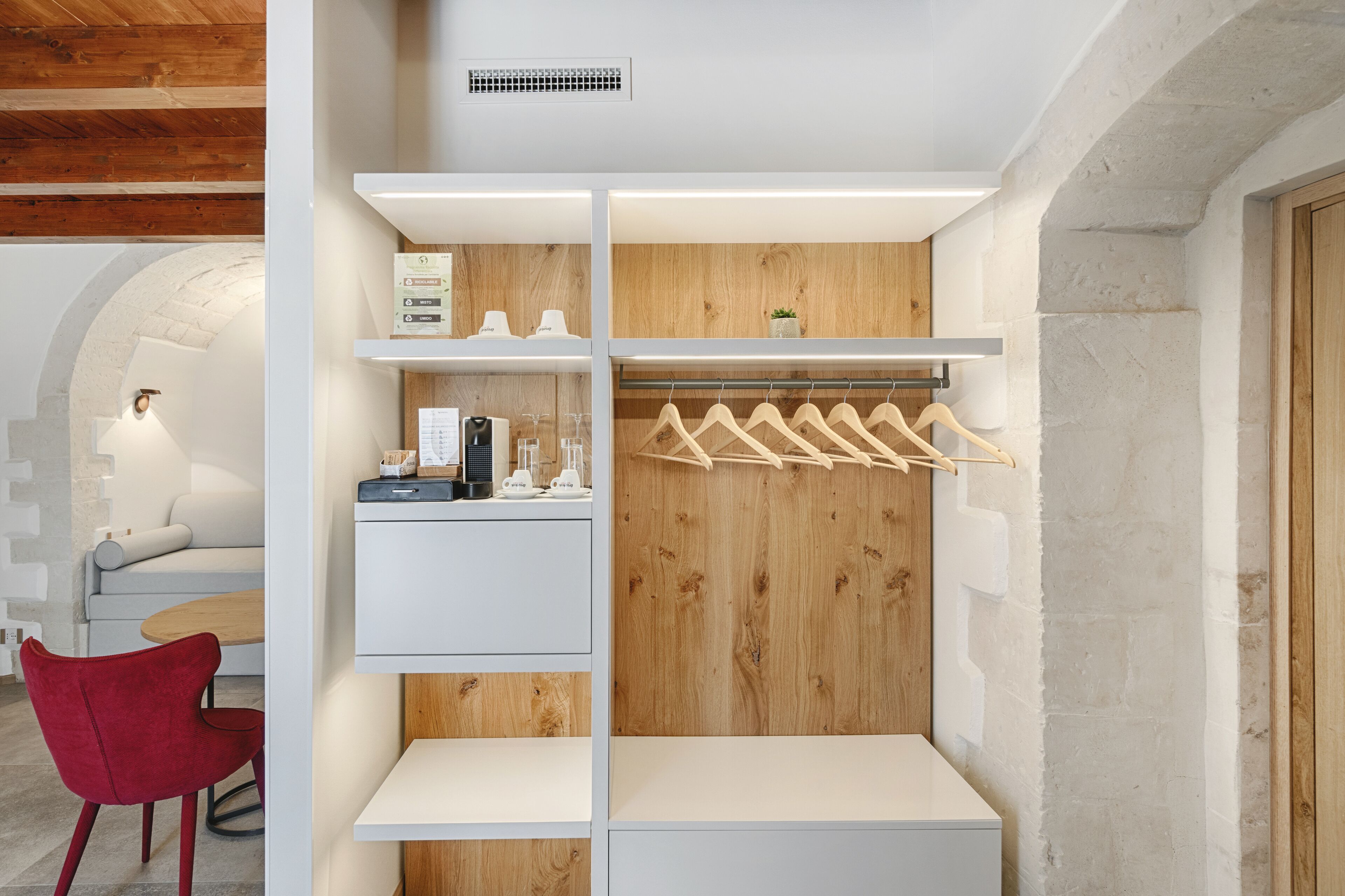 Une chambre moderne avec une armoire en bois, une chaise rouge et une table blanche.