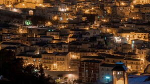 A densely packed hillside town at dusk with illuminated buildings and a prominent dome structure. - Dimora Bonafede Ibla Design Rooms (Ragusa)