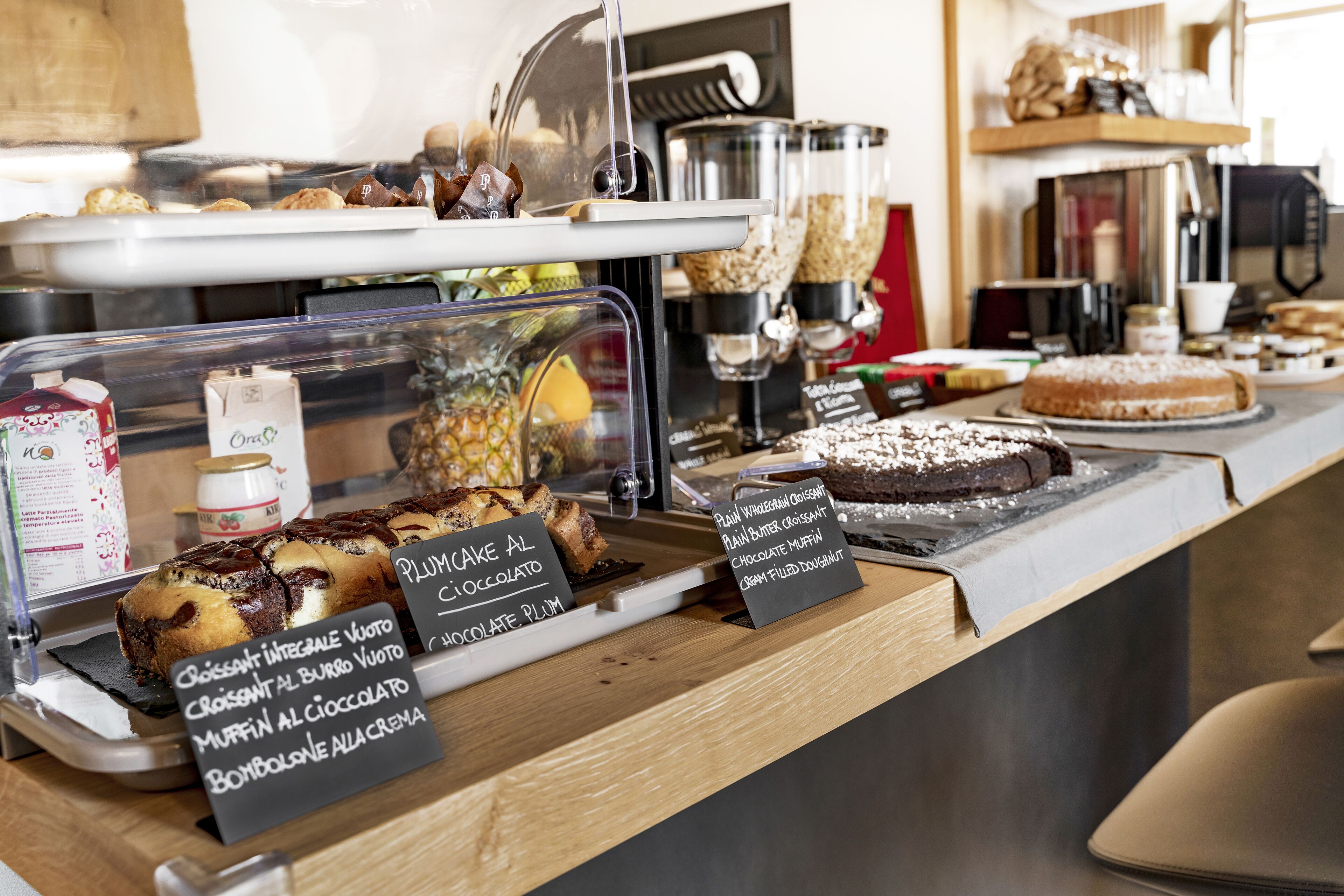 A bakery display with various pastries and desserts, including a chocolate cake and muffins.