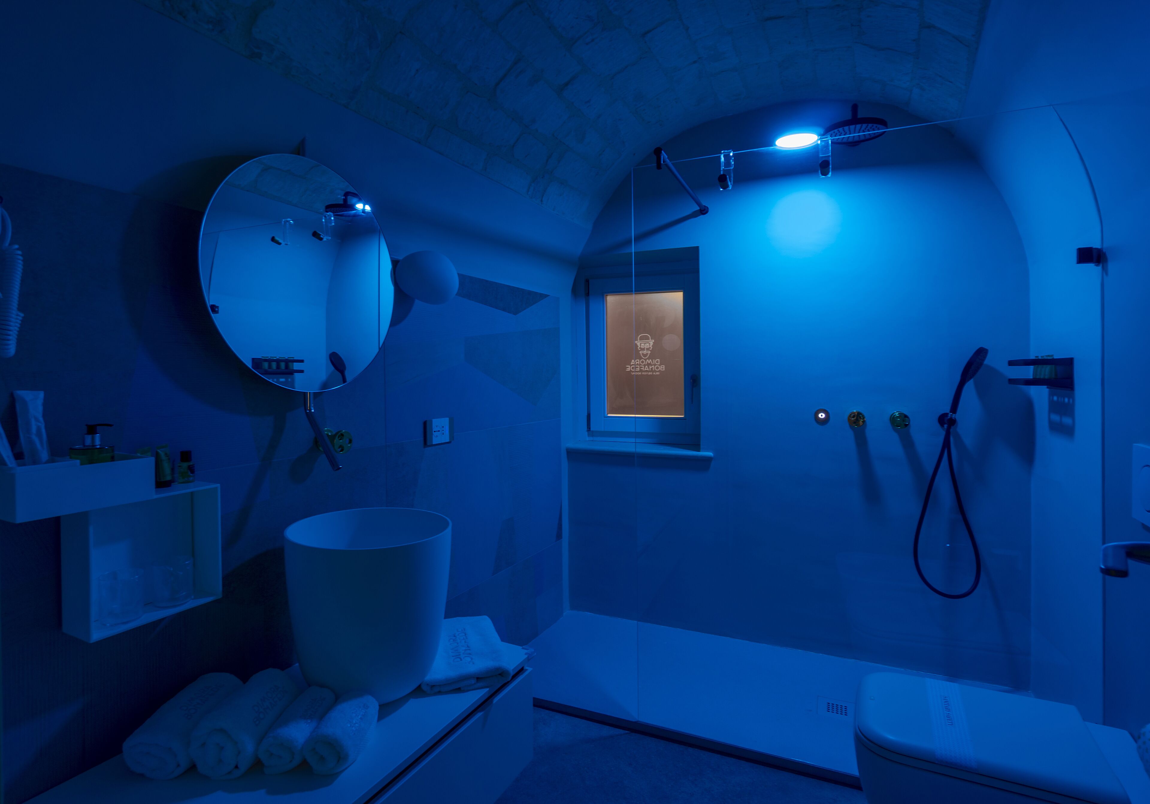 A bathroom with a large mirror, a sink, a toilet, and a shower area.