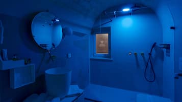 A bathroom with a large mirror, a sink, a toilet, and a shower area.