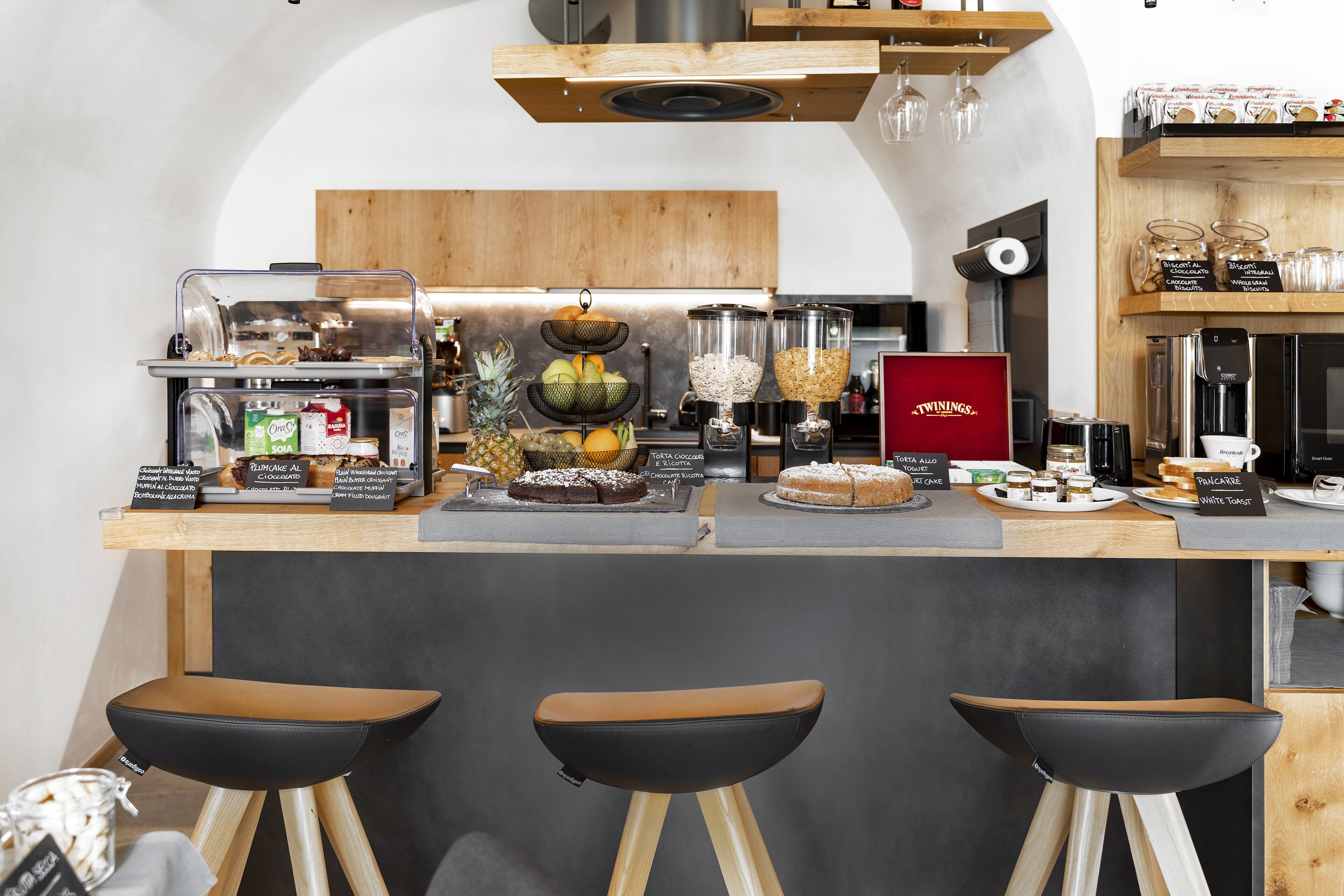 Un espace bar avec des tabourets, une machine à café et divers produits alimentaires exposés sur le comptoir.