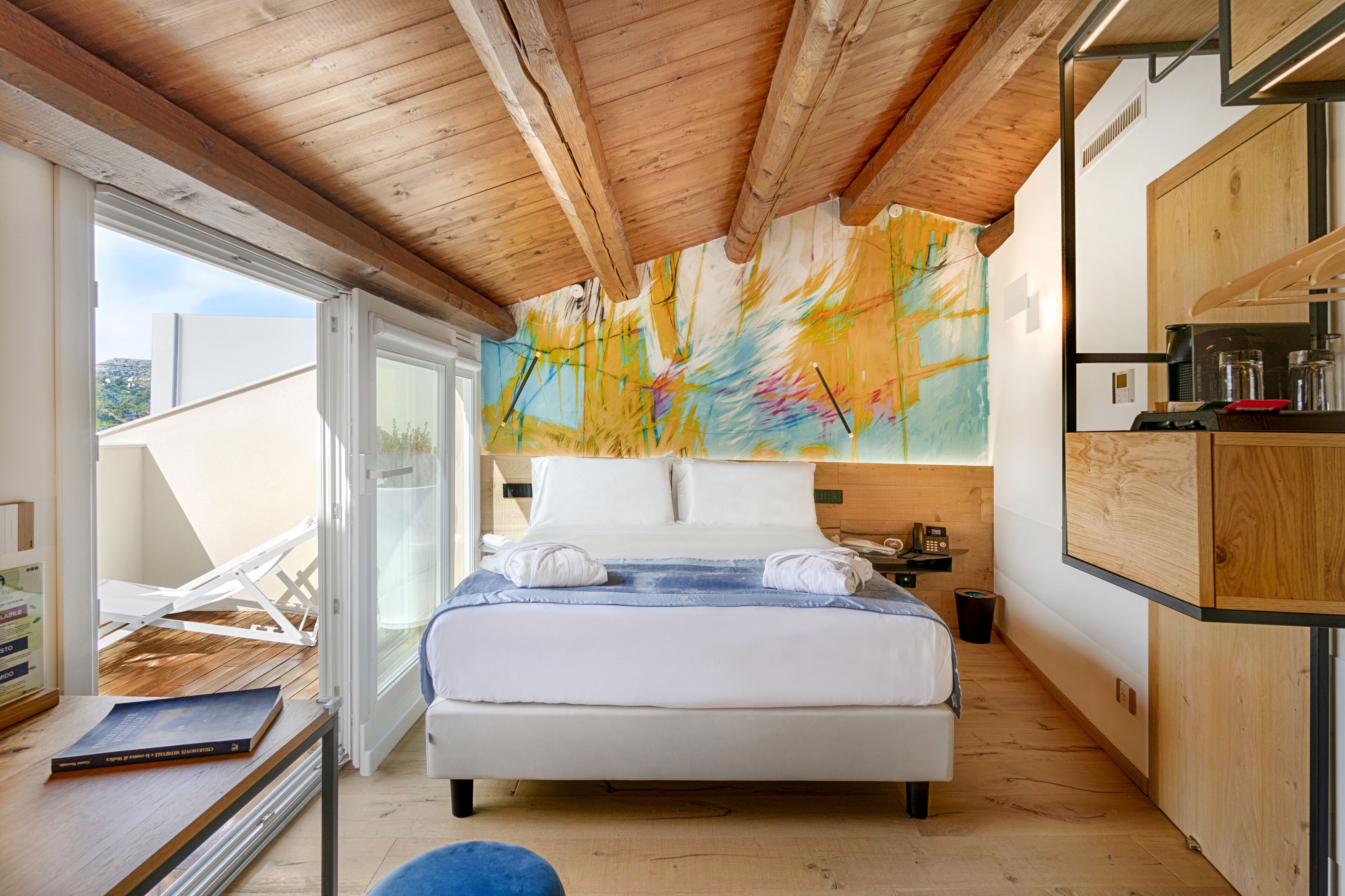 A modern bedroom with a large bed, a wooden ceiling, and a colorful abstract painting on the wall.