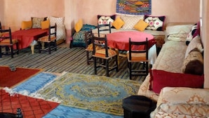 Ein traditionell eingerichteter Raum mit einer Couch, Stühlen, einem gemusterten Teppich und einer dekorativen Wandteppich.