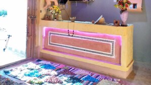 Ein Empfangsbereich mit einem Holztisch, einer hängenden Leuchte und einem farbenfrohen Teppich.
