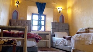 Ein Zimmer mit zwei Betten, einem Schlafsofa, einem Sessel und einem Fenster mit Vorhängen.