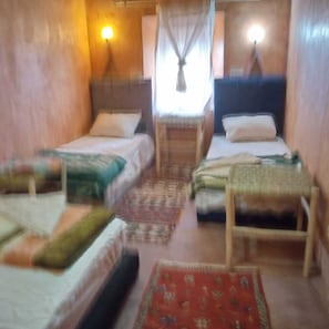 A room with two beds, a small table, and a window with curtains.