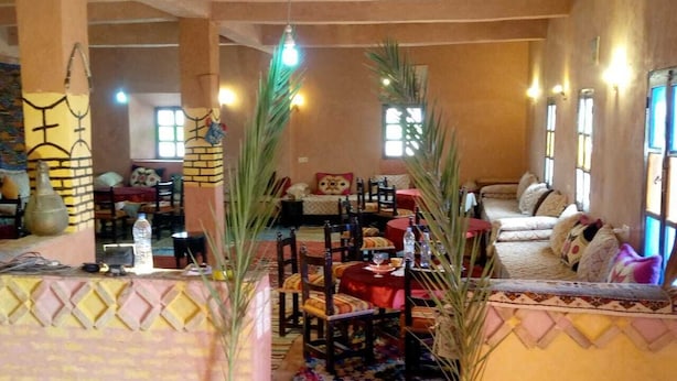 Ein geräumiger Raum mit hoher Decke, einer zentralen Sitzecke mit Sofa und Sesseln sowie einem gemusterten Teppich.