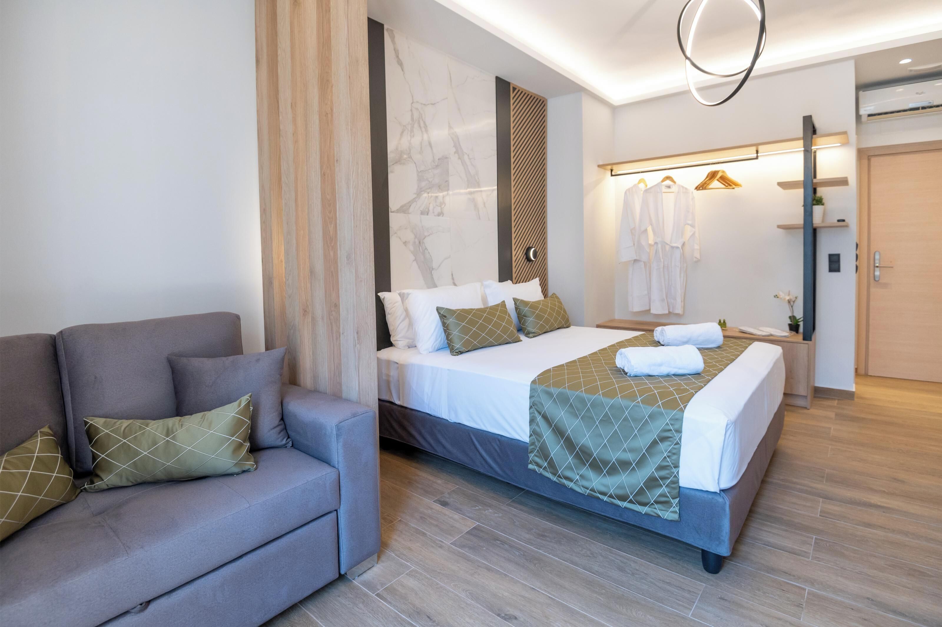 Ett modernt hotellrum med en säng, en soffa, en garderob och en spegel.