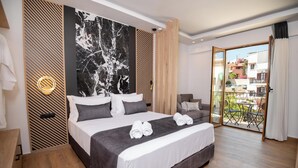 Una habitación de hotel moderna con una cama grande, vistas al balcón exterior y una pared de mármol.