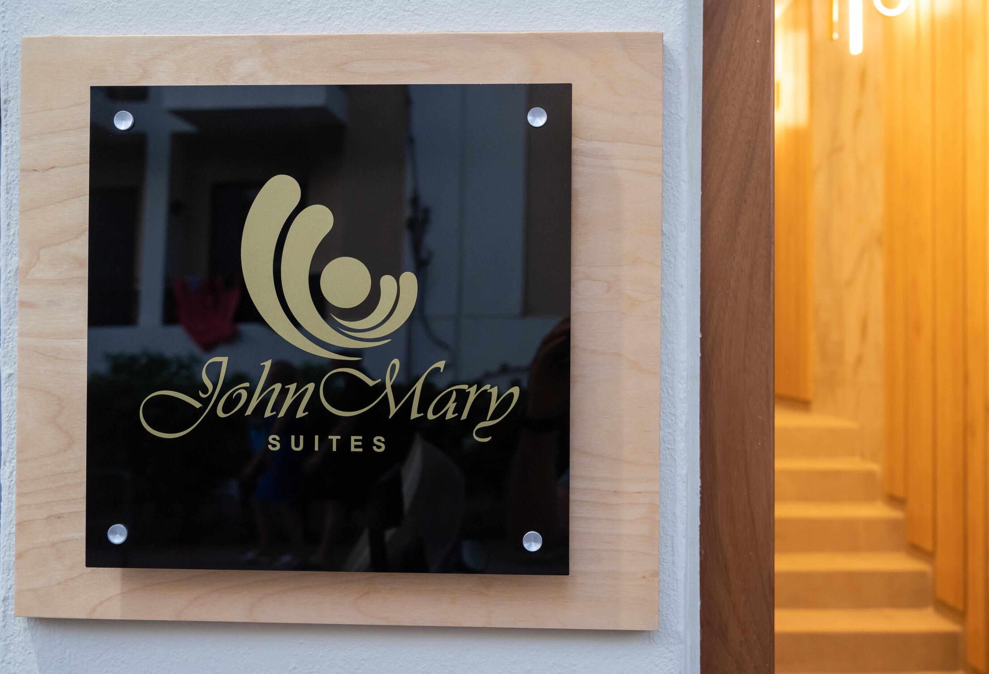 A framed sign with the text "John Mary Suites" and a stylized logo.
