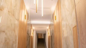 Una escalera moderna con paredes de mármol y paneles de madera, que conduce a un rellano.