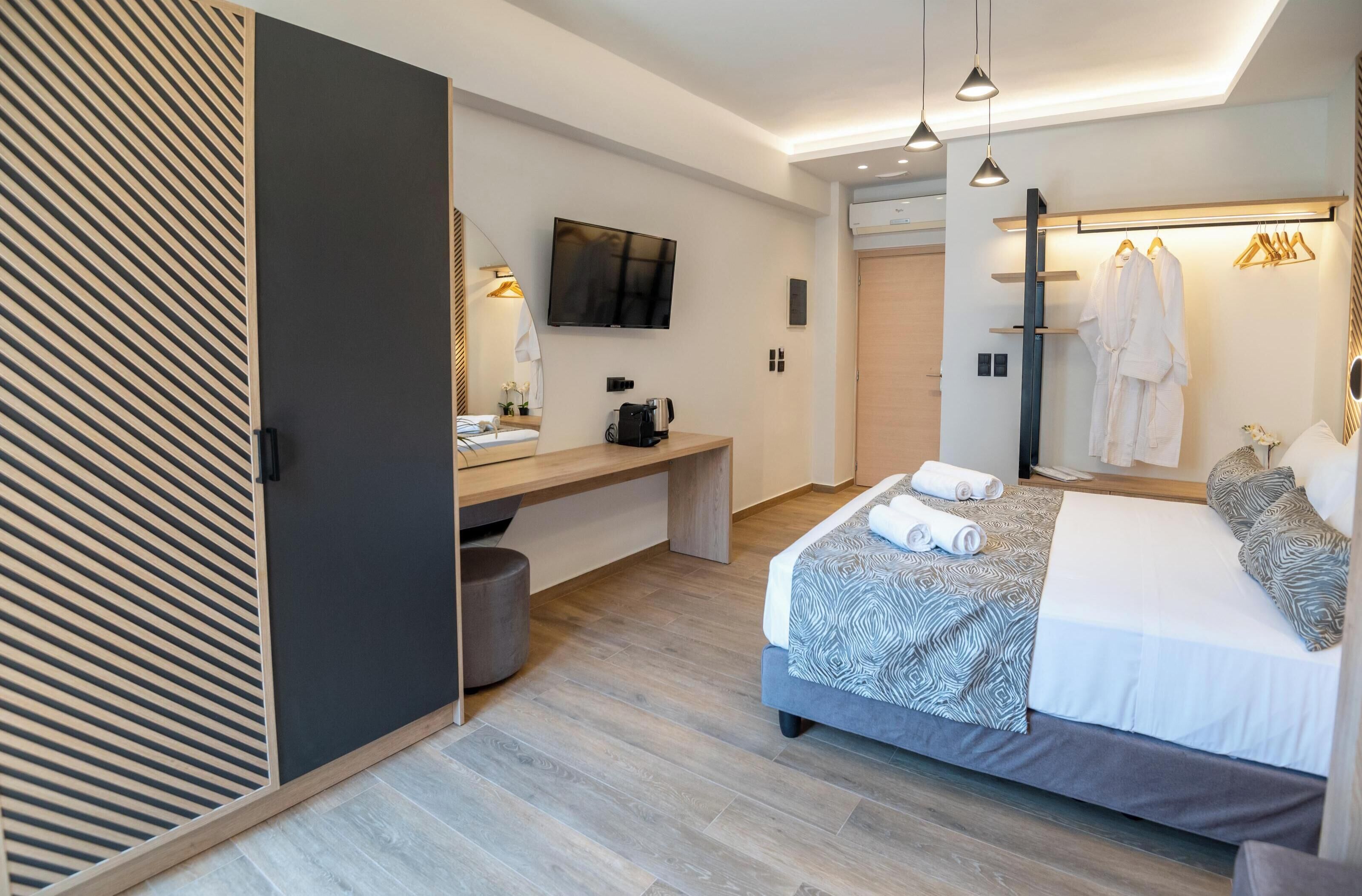 Una habitación de hotel moderna con cama, mesita de noche, televisión y espejo.