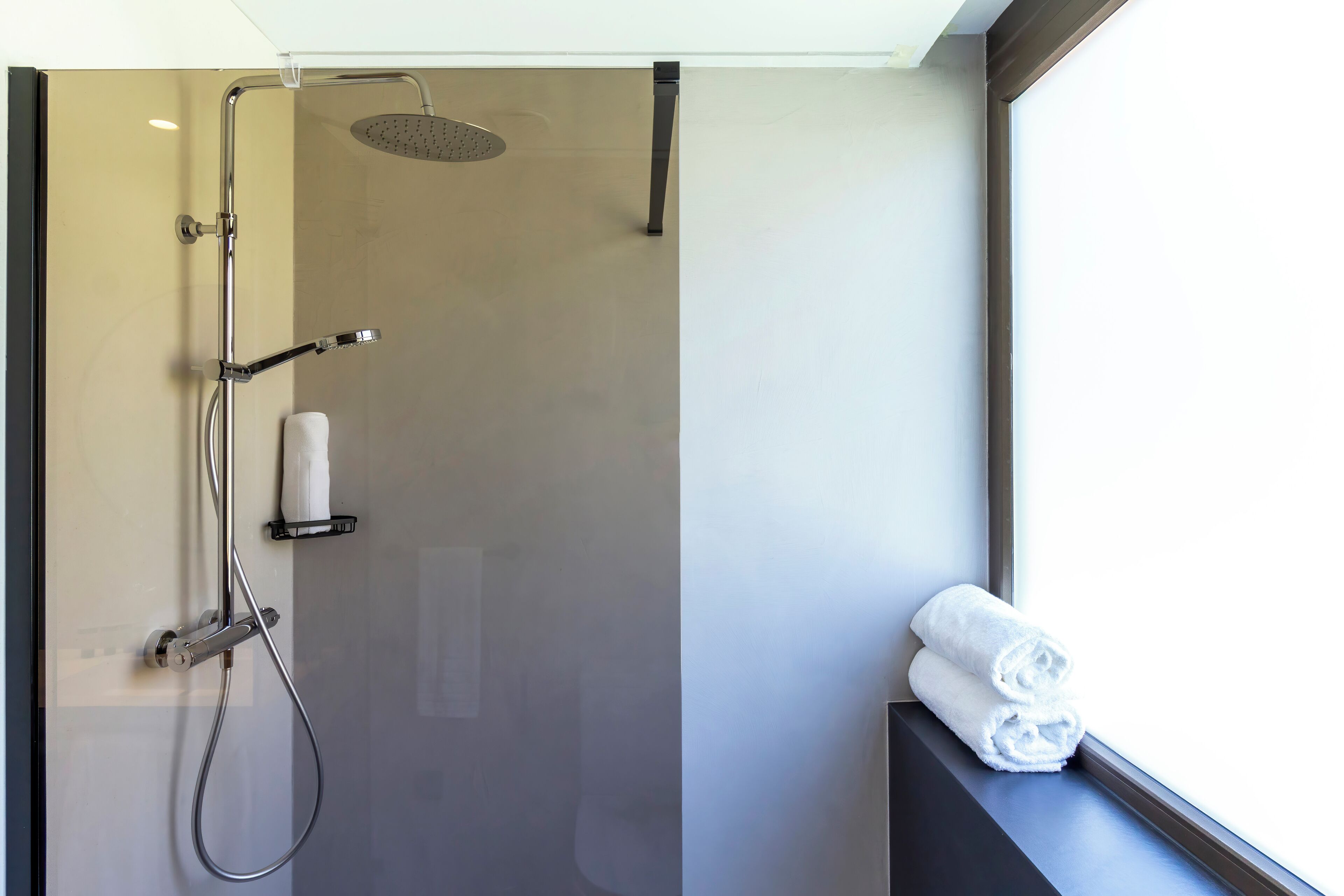 Ein modernes Badezimmer mit Duschkabine aus Glas, Handtuchhalter und einem Fenster mit Blick.