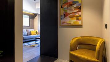 Um interior moderno com uma poltrona amarela, uma pintura abstrata colorida e uma sala de estar com sofá e almofadas.