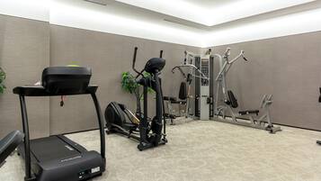 Un gimnasio con cinta de correr, elíptica y máquinas de pesas.