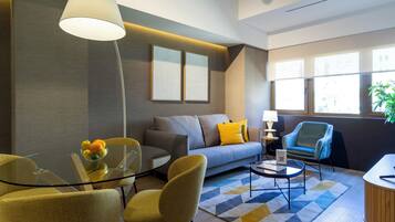 Una sala de estar moderna con un sofá, sillones amarillos, una mesa de vidrio con fruta y una lámpara.